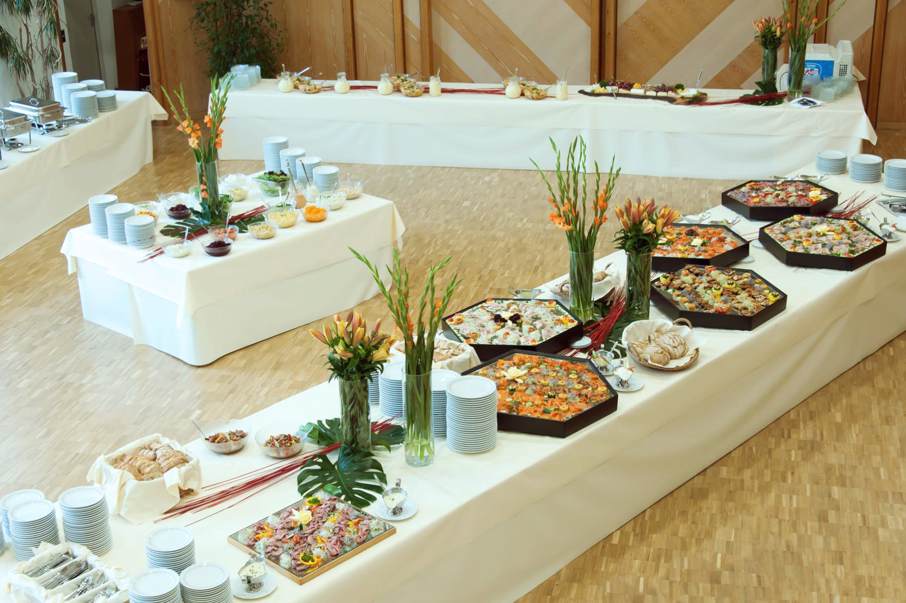 Angerichtetes Buffet auf weißer Tischdecke und Blumenschmuck
